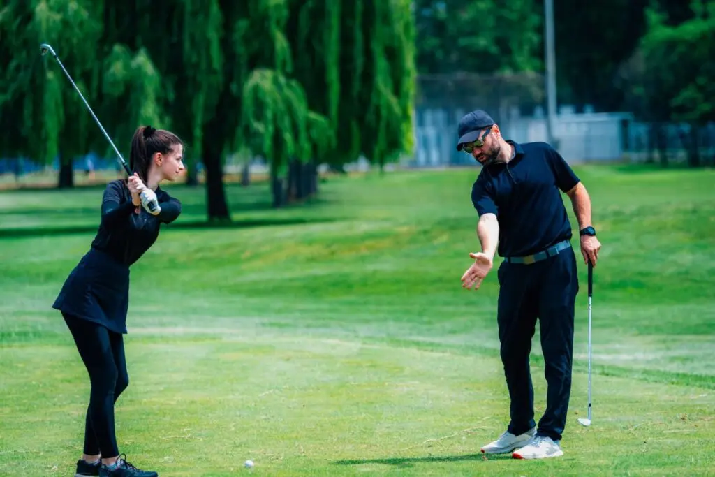 Playing golf. Young woman playing golf with golf instructor